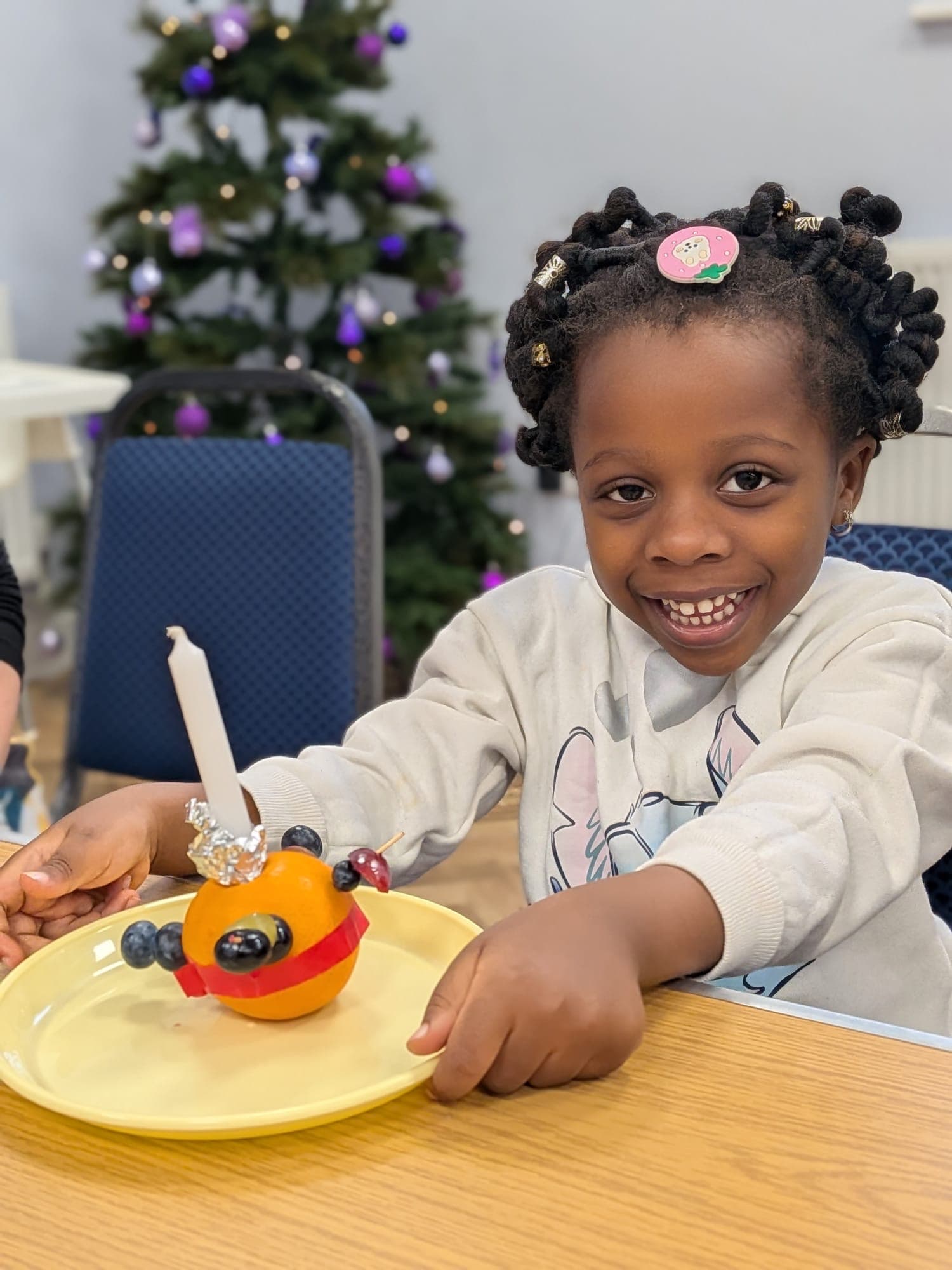 Kachi smiling at a table with a festive fruit decoration